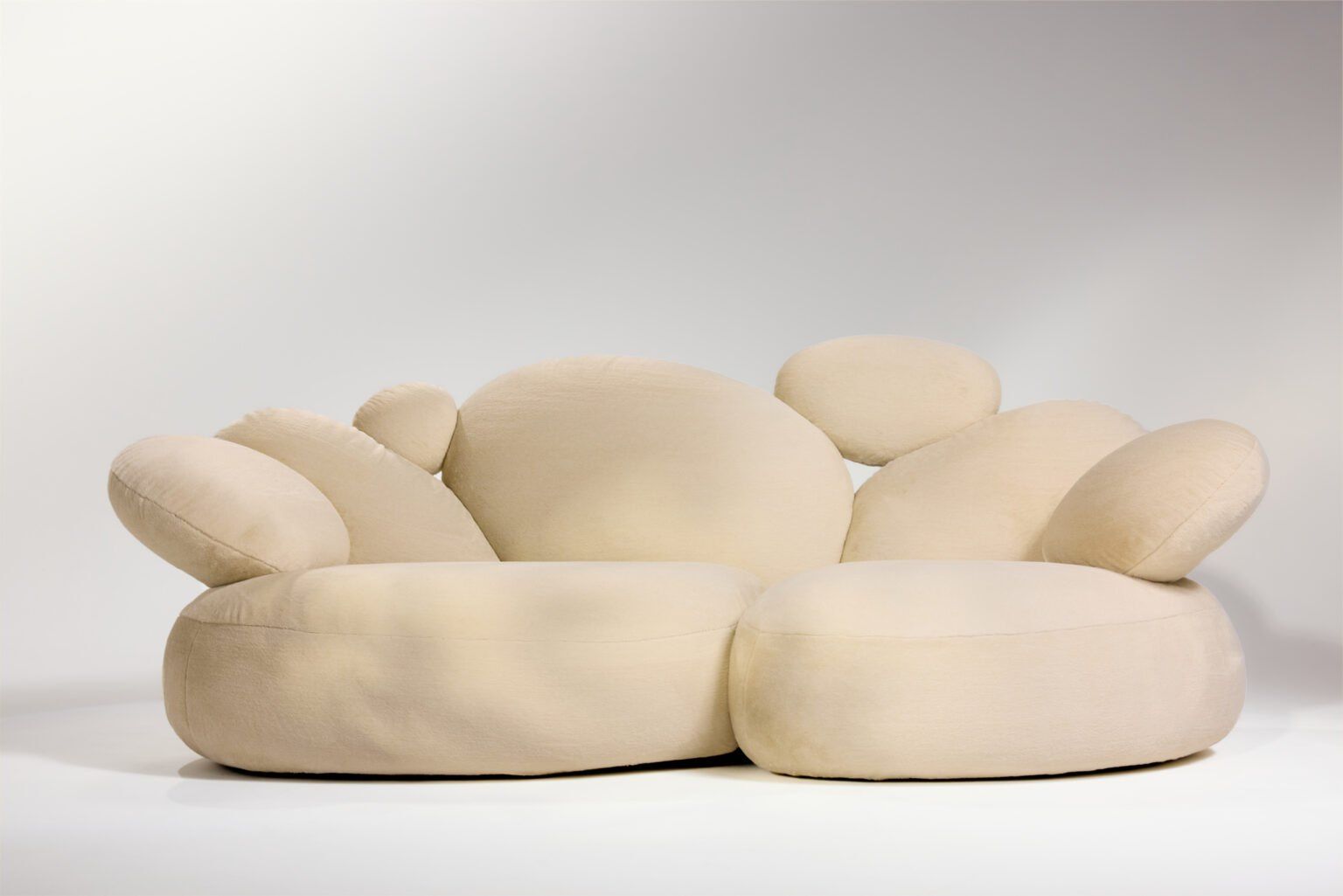 Kremowa sofa Orbs z siedzisk i oparć w kształcie owalnych kamieni, na jasnoszarym tle