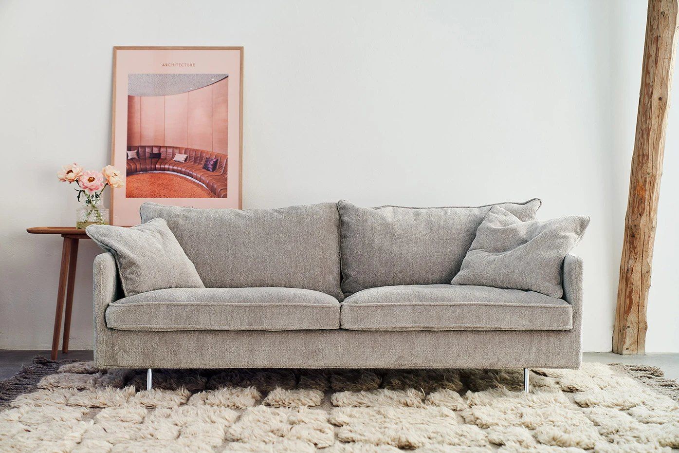 Jasnoszara trzyosobowa sofa Julia na chromowanych nóżkach, na kremowym wełnianym dywanie
